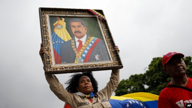 ARCHIVO - Una integrante de la milicia venezolana muestra una foto de Nicolás maduro en Caracas, el 28 de septiembre de 2024.