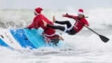 A participant falls off his paddle board at the annual Surfing Santas Christmas Eve event in Cocoa Beach, Florida, Dec. 24, 2024. 