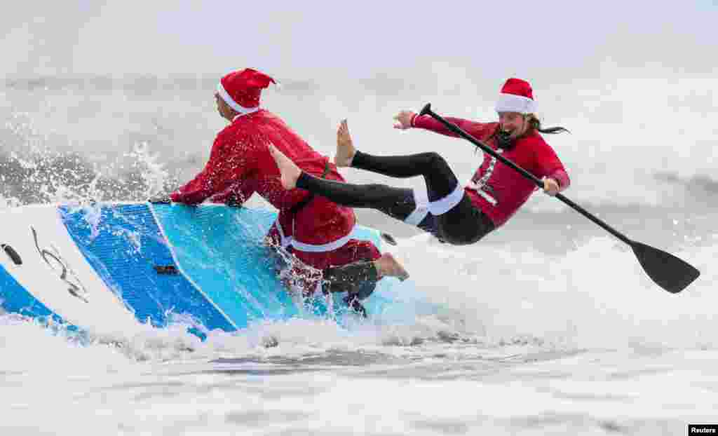 A participant falls off his paddle board at the annual Surfing Santas Christmas Eve event in Cocoa Beach, Florida.