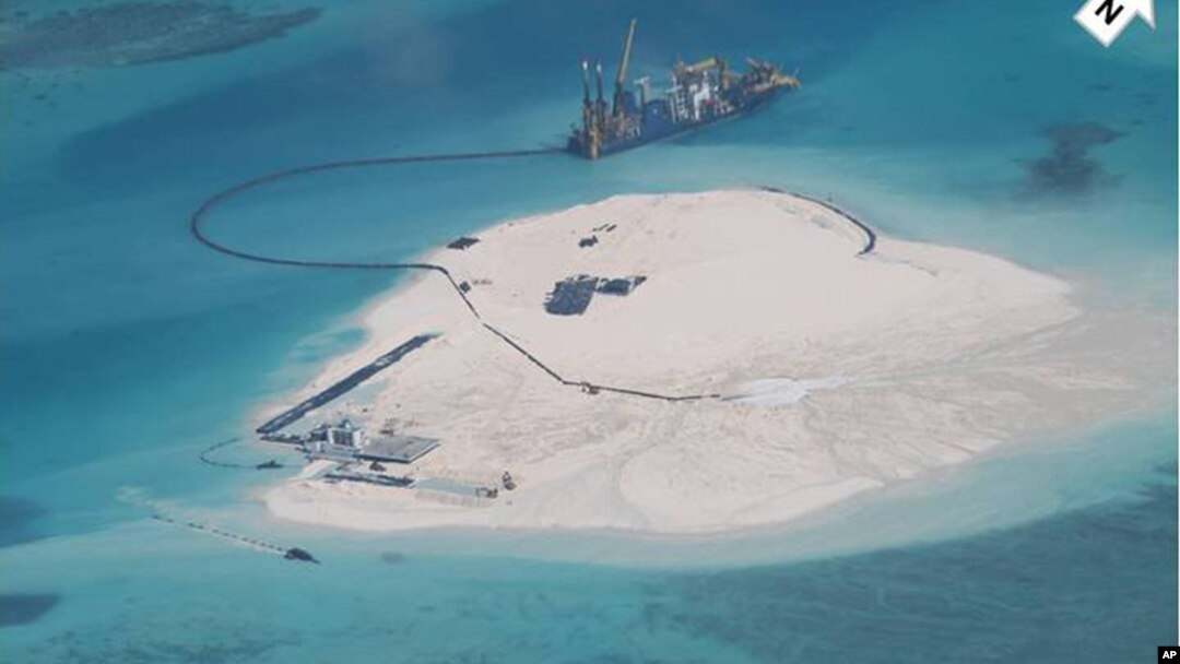 FILE - In this photo taken by surveillance planes and released May 15, 2014 by the Philippine Department of Foreign Affairs, a Chinese vessel, top center, is used to expand structures and land on the Johnson Reef, called Mabini by the Philippines and Chigua by China.