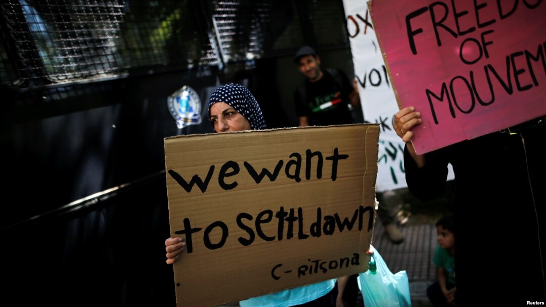 A Syrian refugee holds a banner during a demonstration outside the German embassy against delays in reunifications of refugee families from Greece to Germany, in Athens, Greece, Aug. 2, 2017. 