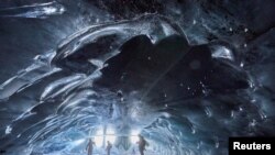 People stand in the Mill, a 20-meter-long natural ice cave, at the Glacier 3000 ski resort in Les Diablerets, Switzerland.