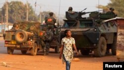 A woman walks past French peacekeeping troops in a street of the capital Bangui, Central African Republic, Jan. 17, 2014.