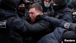 Law enforcement officers restrain a demonstrator during a rally of entrepreneurs and representatives of small businesses amid the COVID-19 outbreak in Kyiv, Ukraine, Dec. 15, 2020.