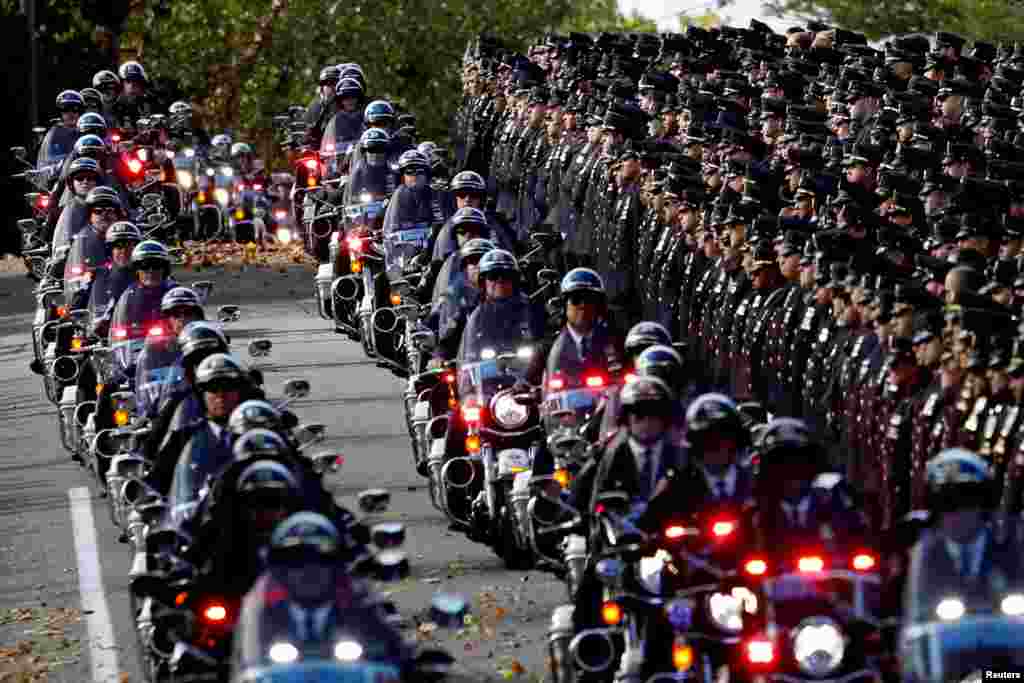 A procession of police motorcycles pass officers lining the street at the funeral service for New York City Police Department (NYPD) officer Brian Mulkeen at the Sacred Heart Church in Monroe, New York.