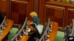 Smoke rises after Kosovo opposition lawmaker Donika Kada Bujupi ignites a tear-gas canister, disrupting Parliament's session for the third time in row, Pristina, Oct. 23, 2015.