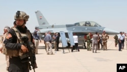 FILE - A member of the Iraqi SWAT team stands guard as security forces and others gather next to a U.S.- made F-16 fighter jet during the delivery ceremony at Balad air base, Iraq, July 20, 2015.