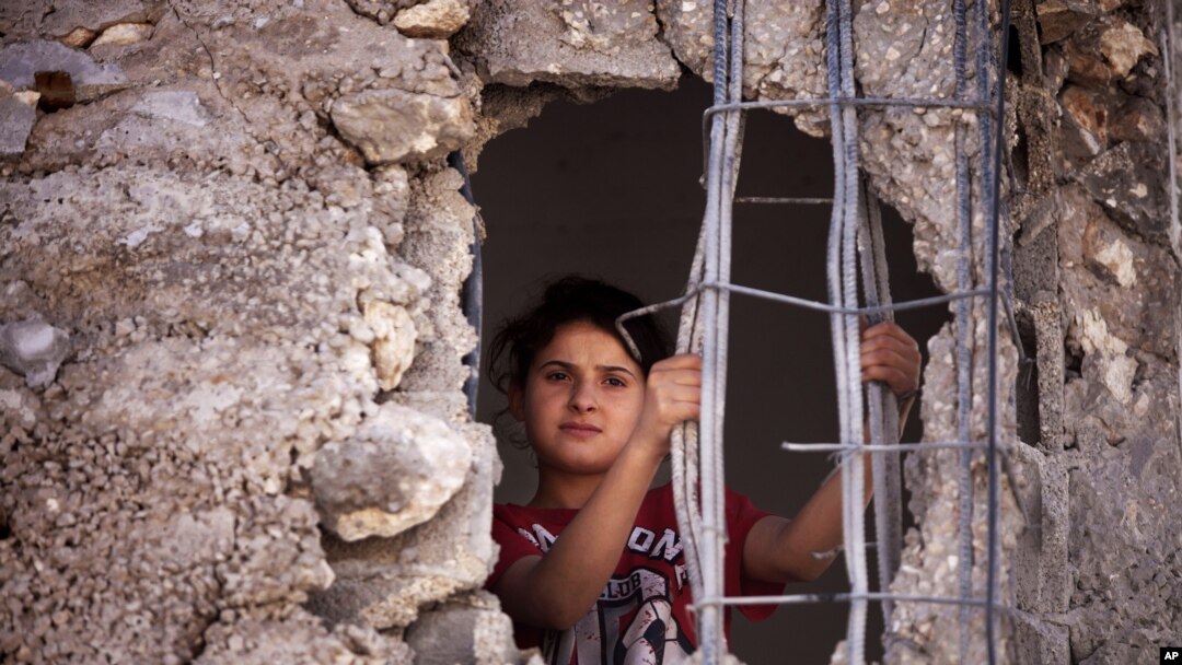 FILE - A Palestinian child looks out from the damaged family home.