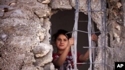 FILE - A Palestinian child looks out from the damaged family home.