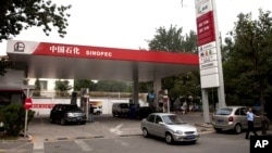 FILE - Motorists pump fuel at a Sinopec gas station in Beijing, China, Aug. 29, 2011. 