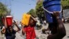 2024 年 3 月 12 日，海地太子港，人们在用塑料桶和其他容器搬运水。