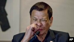 Presiden Filipina Rodrigo Duterte mendemonstrasikan bagaimana pecandu narkoba mengirup zat tersebut dalam konferensi pers di Beijing, Oktober 2016. (AP/Ng Han Guan)