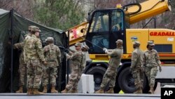 Anggota Garda Nasional mendirikan tenda untuk pusat tes virus corona di lahan parkir FedEx Field di Landover, Maryland, di luar Kota Washington D.C, 21 Maret 2020. (Foto: AP)