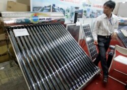 FILE - A solar water heater, left, and a solar panel are seen at Entech Hanoi, an international trade fair on energy efficiency and the environment, at the Giang Vo Exhibition Center in Hanoi, Vietnam.