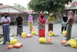 FILE - Rohingya refugees wearing protective masks keep a social distance wait to receive goods from volunteers, during the outbreak of COVID-19, in Kuala Lumpur, Malaysia, April 7, 2020.