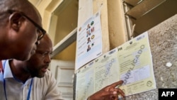 Two men review the voter results posted outside a classroom used as a polling station in Beira on October 10, 2024, the day after Mozambique's national election.