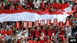 Suporter Indonesia bersorak untuk memberi semangat tim Garuda Muda di Stadion Abdullah Bin Khalifa di Doha, Qatar. 