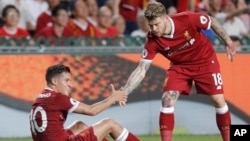 Philippe Coutinho de Liverpool, assis sur la pelouse, à gauche, tient la main de son coéquipier, Alberto Moreno, lors d’un match à Hong Kong, Chine, 22 juillet 2017. 