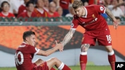 Philippe Coutinho de Liverpool, assis sur la pelouse, à gauche, tient la main de son coéquipier, Alberto Moreno, lors d’un match à Hong Kong, Chine, 22 juillet 2017. 