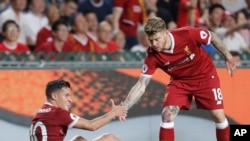 Philippe Coutinho de Liverpool, assis sur la pelouse, à gauche, tient la main de son coéquipier, Alberto Moreno, lors d’un match à Hong Kong, Chine, 22 juillet 2017. 