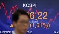 A currency trader walks by the screen showing the Korea Composite Stock Price Index (KOSPI) at the foreign exchange dealing room in Seoul, South Korea, April 9, 2020.