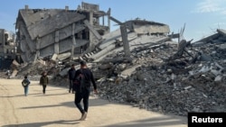 Palestinians walk past the rubble of destroyed houses during a ceasefire between Israel and Hamas in Khan Younis in the southern Gaza Strip, March 6, 2025. 