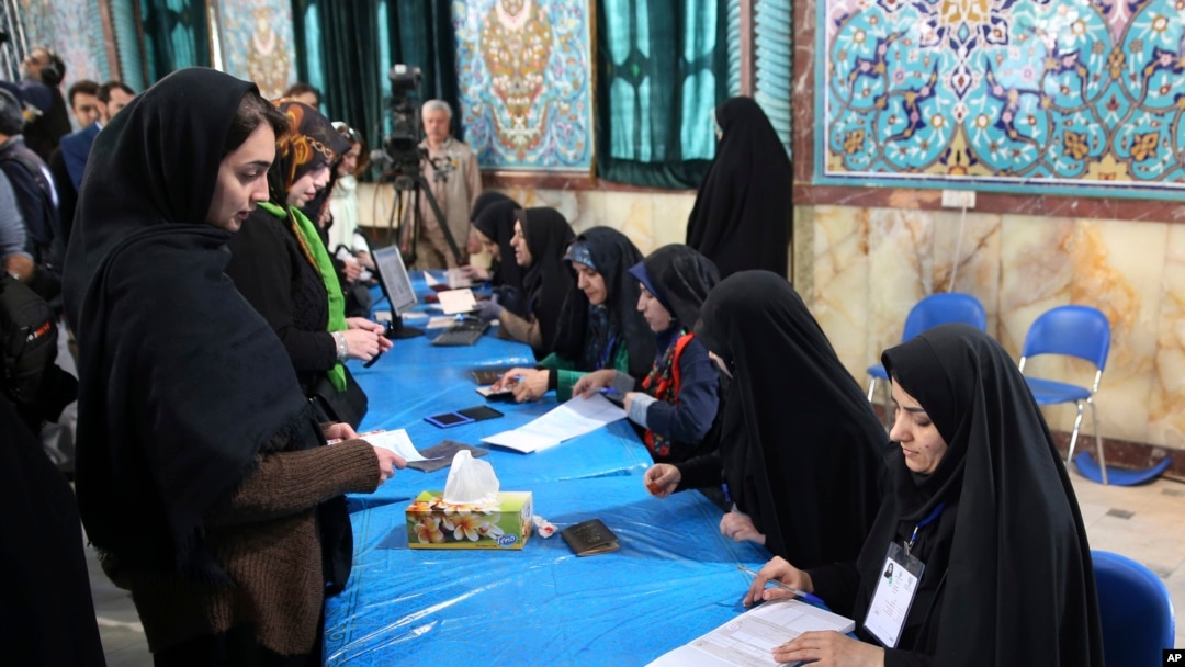 Peserta pemilu Iran (kiri) tiba di TPS untuk mengikuti pemungutan suara parlemen di Teheran, Iran (26/2). 