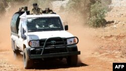 FILE - Syrian fighters stand at the back of a pick-up as they participate in a mock battle in anticipation of an attack by the regime on Idlib province and the surrounding countryside, during a graduation of new Hayat Tahrir al-Sham (HTS) members at a camp in the countryside of northern Idlib province, Aug. 14, 2018. 