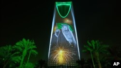 FILE - In this photo taken Sept. 24, 2017, and released by the Saudi Culture and Information Ministry, an image of King Salman and Crown Prince Mohammed bin Salman are projected on the Kingdom Tower in Riyadh, Saudi Arabia. A court in Saudi Arabia sentenced a columnist to five years in prison for insulting the Saudi royals.