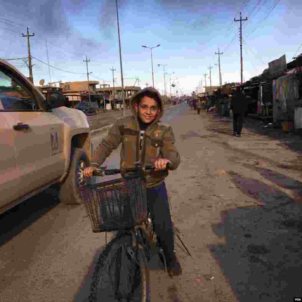 Seorang anak laki-laki mengendarai sepedanya menuju pasar di kota Qayyarah, sebelah selatan Mosul, Desember 2016. (VOA/Kawa Omar)