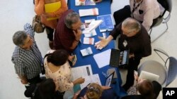 FILE - Alex Pereira of the U.S. Census Bureau, right, talks with job applicants about temporary positions available with the 2020 Census, during a job fair in Miami, Sept. 18, 2019.