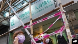 People walk past the entrance of the Hong Kong Professional Teachers' Union in Hong Kong, Aug. 10, 2021. 