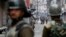 A Kashmiri woman walks as Indian police officers stand guard during a strike called by Kashmiri separatists in Srinagar, February 16, 2013. 