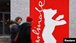 Njerëzit ecin përpara logos së festivalit të filmit në Berlin