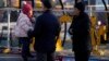 A couple watch a child jump on a trampoline at an amusement park in Beijing, China, Jan. 17, 2022. The number of babies born in China continued to shrink last year in a decade-long trend, official data shows.