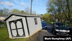 Sebuah kendaraan melintas bangunan kayu yang terseret banjir ke jalanan di Nashville, Tennessee, Minggu, 28 Maret 2021. Hujan lebat di Tennessee mengakibat banjir yang menggenangi rumah dan jalan-jalan.(Foto: Mark Humphrey/AP Photo)