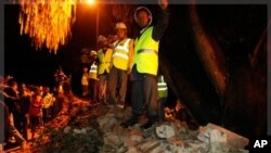 Nepalese rescue workers and people look on after after the British Embassy's compound wall collapsed reportedly killing three pedestrians following an earthquake in Katmandu, Nepal, Sunday, Sept. 18, 2011.