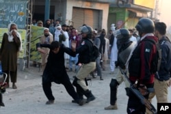 Polisi di Peshawar, Pakistan, memukuli seorang pengunjuk rasa yang bersama lainnya memblokir jalan dekat kantor polisi, menuntut penyerahan pria yang ditangkap karena diduga menghina Al-Quran, 19 November 2024. (Foto: AP/Muhammad Sajjad)