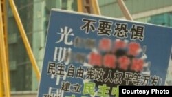 深圳维权人士黄文勋日前再次在深圳市中心繁华地带“举牌”(腾讯微博网民提供)