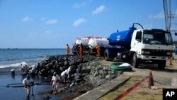 Trabajadores de la estatal Heritage Petroleum Oil and Gas Company limpian un derrame de petróleo que llegó a la playa de Rockly Bay, en Scarborough, suroeste de la isla de Tobago, Trinidad y Tobago, el 11 de febrero de 2024.