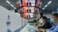 FILE - Media staff work next to screens showing live images of China's President Xi Jinping speaking during the opening ceremony of the China International Import Expo in Shanghai on Nov. 4, 2021.