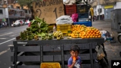 A child eats ice cream near a truck that sells fruit with prices set in US dollars in Caracas, Venezuela, Dec. 11, 2022.