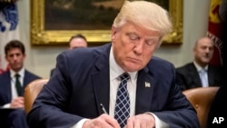 ARCHIVO - El presidente Donald Trump firma una orden ejecutiva en el Salón Roosevelt de la Casa Blanca en Washington, el 25 de abril de 2017.