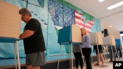 Votantes emiten su voto frente a un mural en un colegio electoral de una escuela primaria el 7 de noviembre de 2023, en Midlothian, Virginia, EEUU.