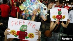 Para penggemar sepak bola menunjukkan poster-poster mendukung demonstran anti pemerintah dalam laga kualifikasi Piala Dunia antara Hong Kong dan Iran di Stadion Hong Kong, China, 10 September 2019. (Foto: Reuters)