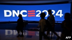 La gente pasa junto a una pantalla antes de la Convención Nacional Demócrata (DNC) en el United Center en Chicago, Illinois, el 15 de agosto de 2024.