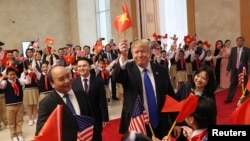 Tổng thống Donald Trump trao lá cờ Mỹ cho Thủ tướng Nguyễn Xuân Phúc và bản thân ông cầm lá cờ Việt Nam để vẫy chào đám đông trong chuyến công du đến Hà Nội vào ngày 27/2/2019.