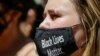 A women wears a protective mask as she joins protesters near Trump Tower as part of a solidarity rally calling for justice over the death of George Floyd, and to highlight police brutality nationwide, June 12, 2020, in New York.