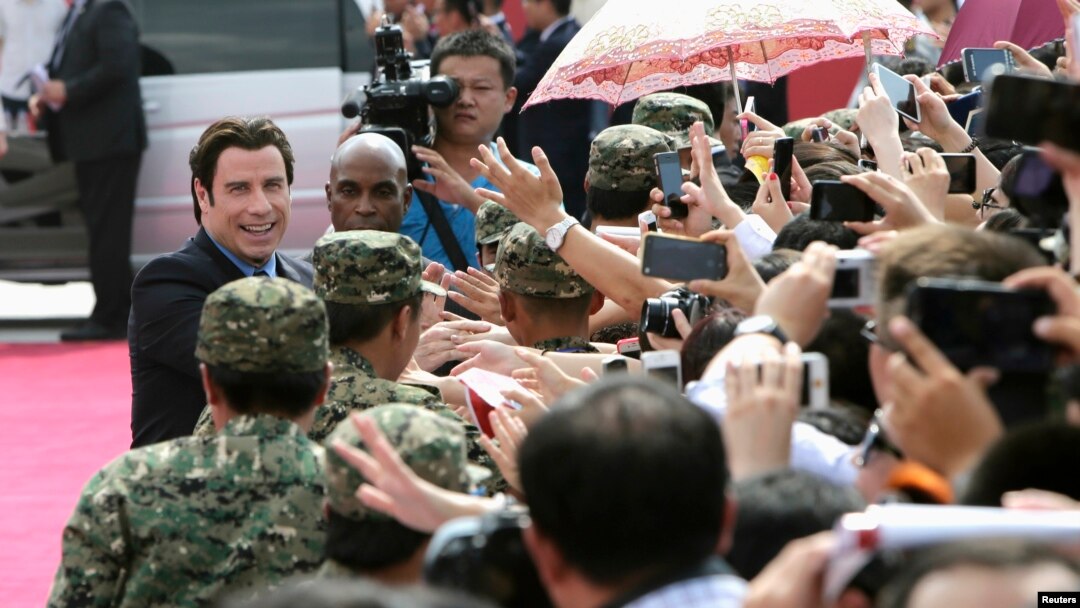 American actor John Travolta (L) shakes hands with fans as he arrives for the launch ceremony of the Qingdao Oriental Movie Metropolis on the outskirts of Qingdao, China, September 22, 2013.