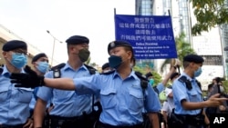 Police officers raise a warning flag against supporters gathered outside a court in Hong Kong, March 1, 2021.